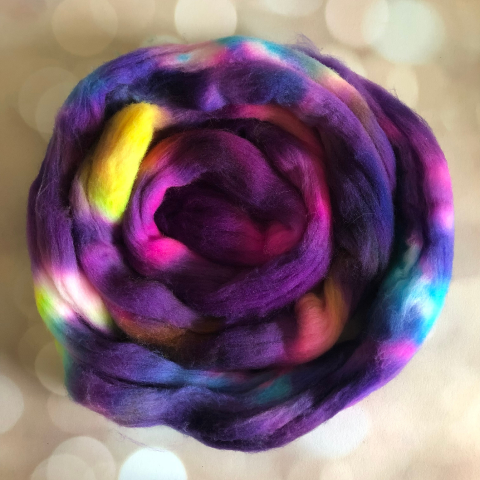 Dyed rambouillet top all coiled up in purple with bits of neon yellow, pink and blue.