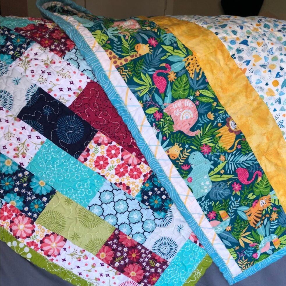 Two colorful quilts lay on a bed.