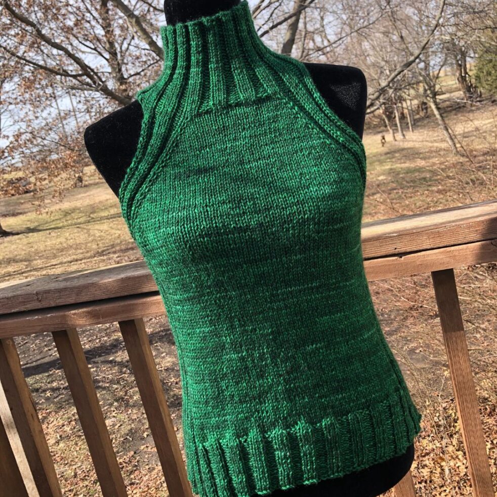 A handknit, turtleneck tank top in Emerald green yarn with ribbing at the neck, sides and bottom.